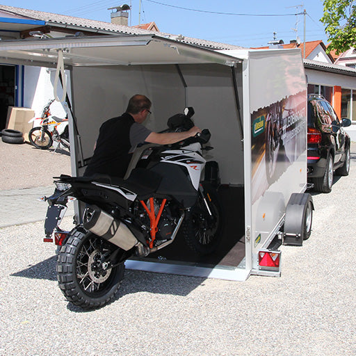 UNSINN Absenkanhänger mit einem Kofferaufbau, wird mit einem Motorrad beladen