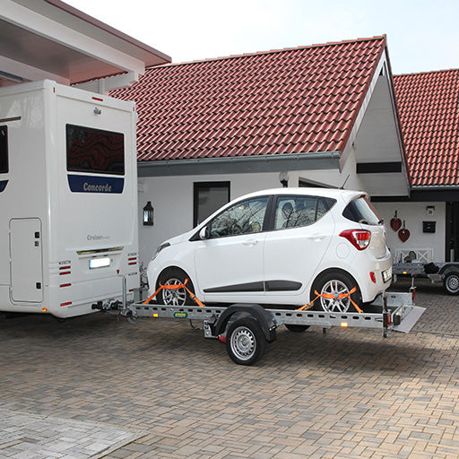 UNSINN Absenkanhänger an einem Wohnmobile angehängt und mit einem kleinen Auto beladen